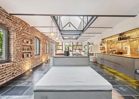 Exklusives Landhaus mit Loft-Charme in Pulheim - Offene Design-Küche mit Kochinsel und Backsteinwänden