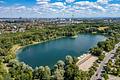Direktlage am Lerchenauer See: 3.876 m² Ufergrundstück mit Baugenehmigung für Hotel mit Biergarten - Blick über den See mit Münchner Skyline und Alpen